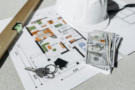 Money and Keys Lying on a Paper with a House Plan