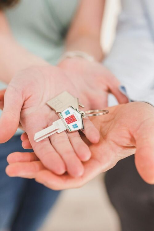 People Holding a House Shaped Key