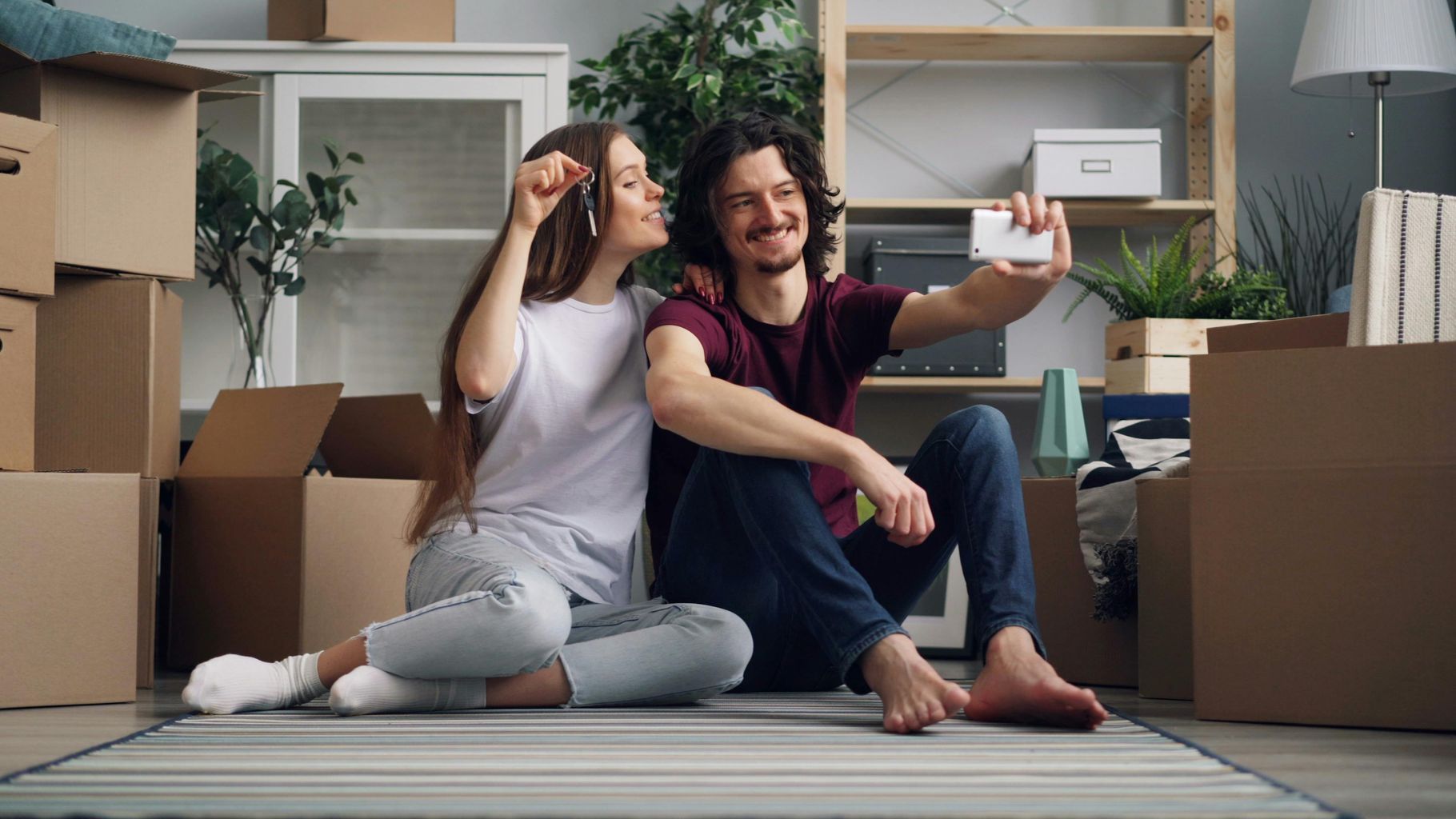 Smiling Couple Sitting with House Keys and Taking Selfie