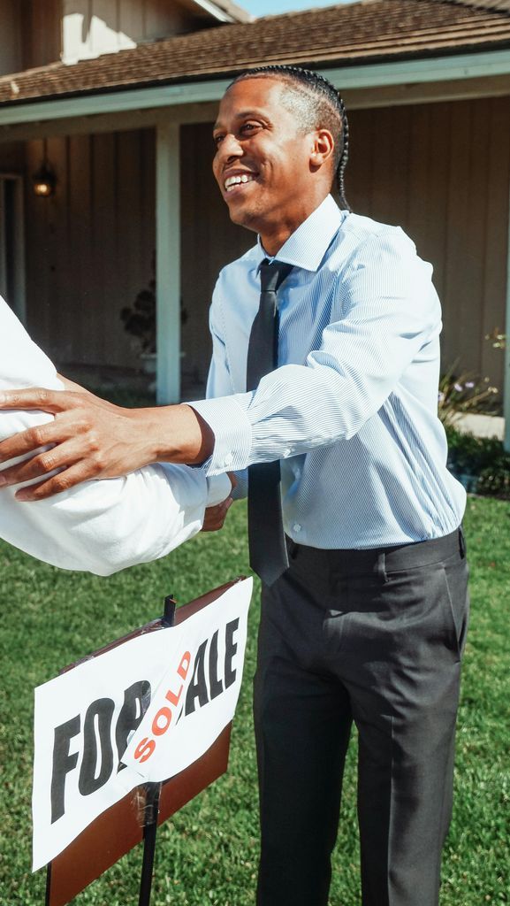 Man Standing Beside a For Sale Sign