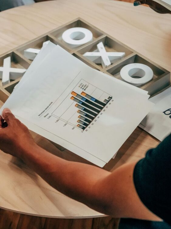 Person Holding White Printer Paper on Wooden Table