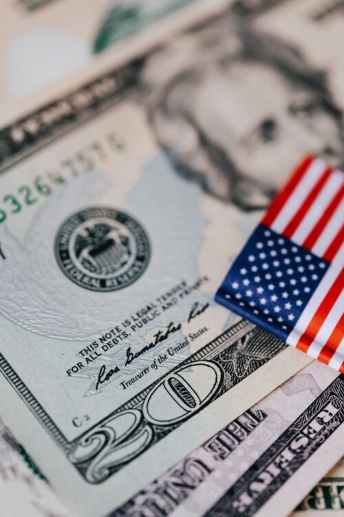 Closeup of small bright American flag placed on various dollar bills