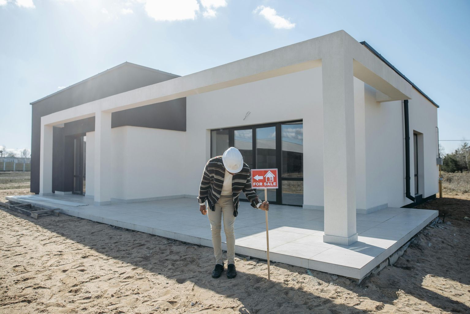 A Man Posting a For Sale Sign Near a House