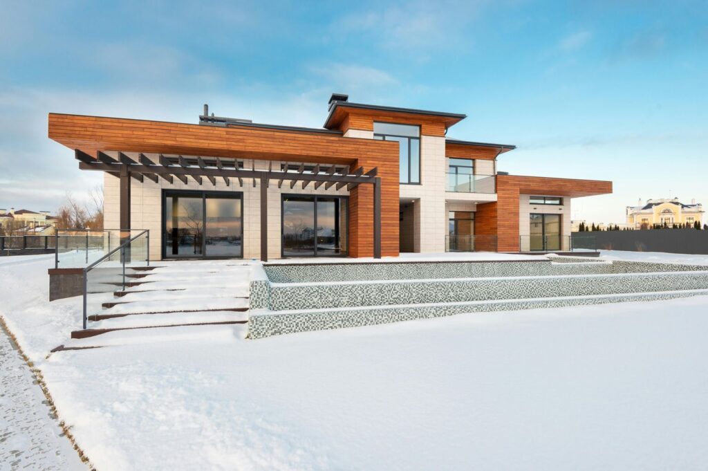 Exterior view of contemporary residential house with terrace and large windows located in suburban area in winter day