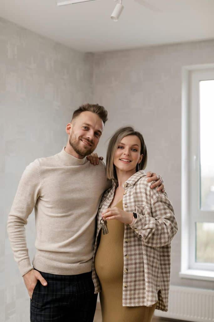 A Pregnant Woman with Her Husband Holding the Keys to Their New Home