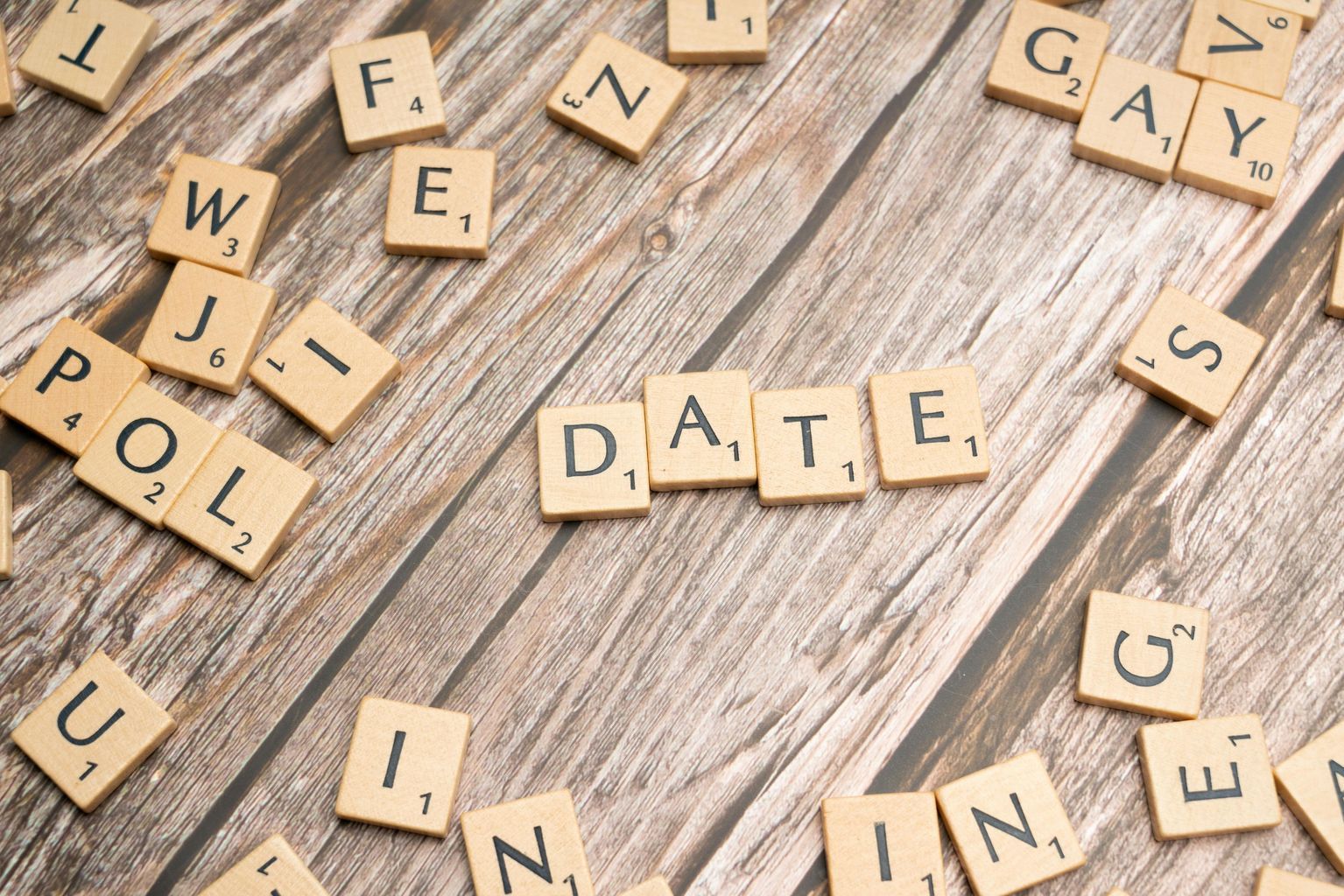 Scrabble letters spelling out the word date on a wooden table