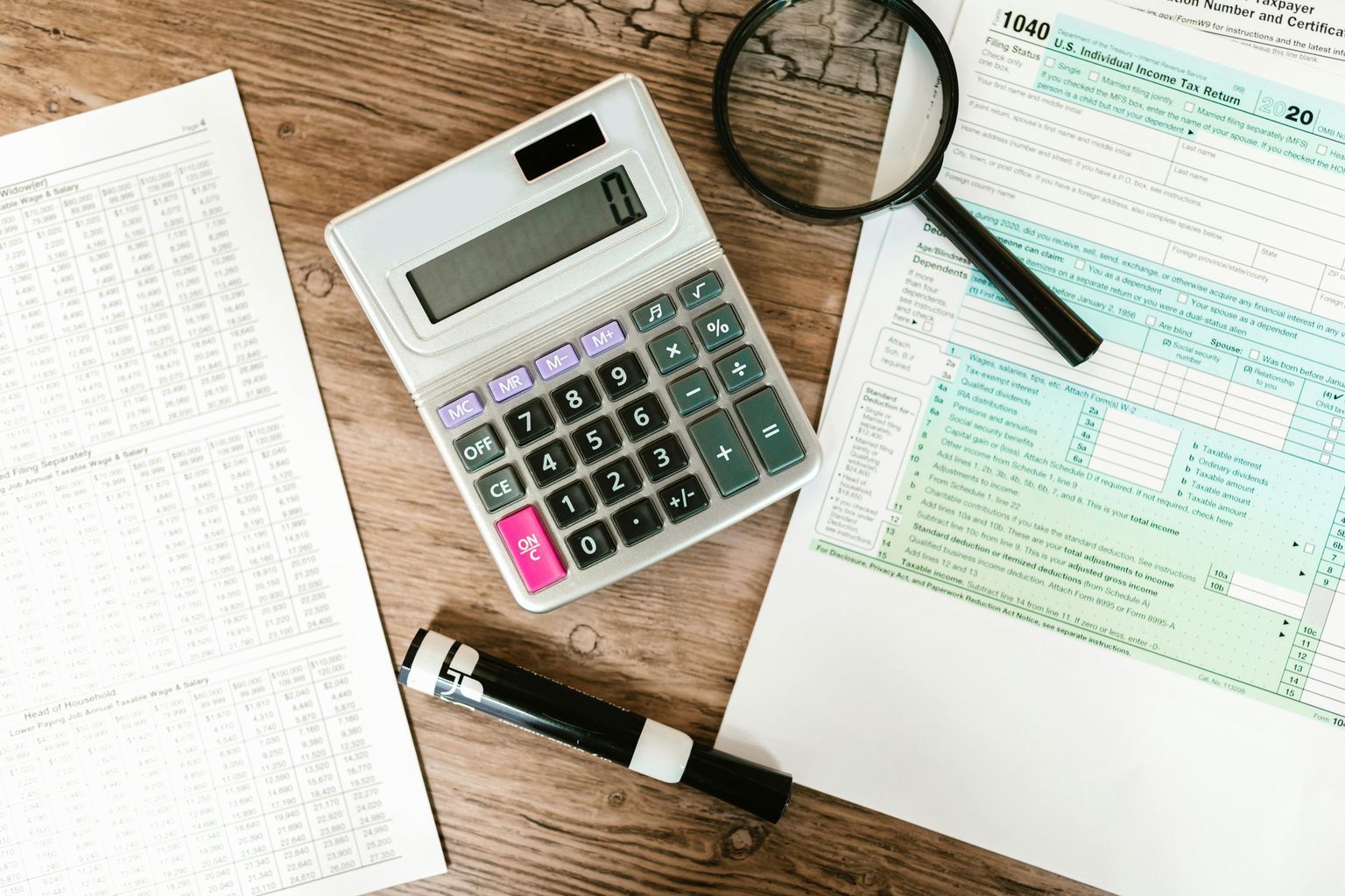 Gray Calculator and Black Magnifying Glass on Brown Wooden Surface